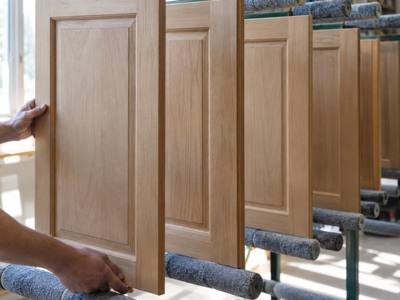 A bare wood cabinet door is cleaned and prepared for its new finish.